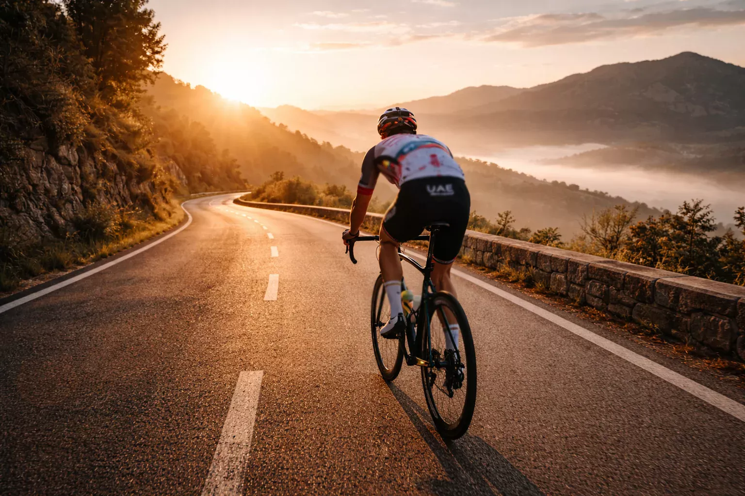 Ciclista profesional entrenando en solitario por una carretera de montaña al amanecer