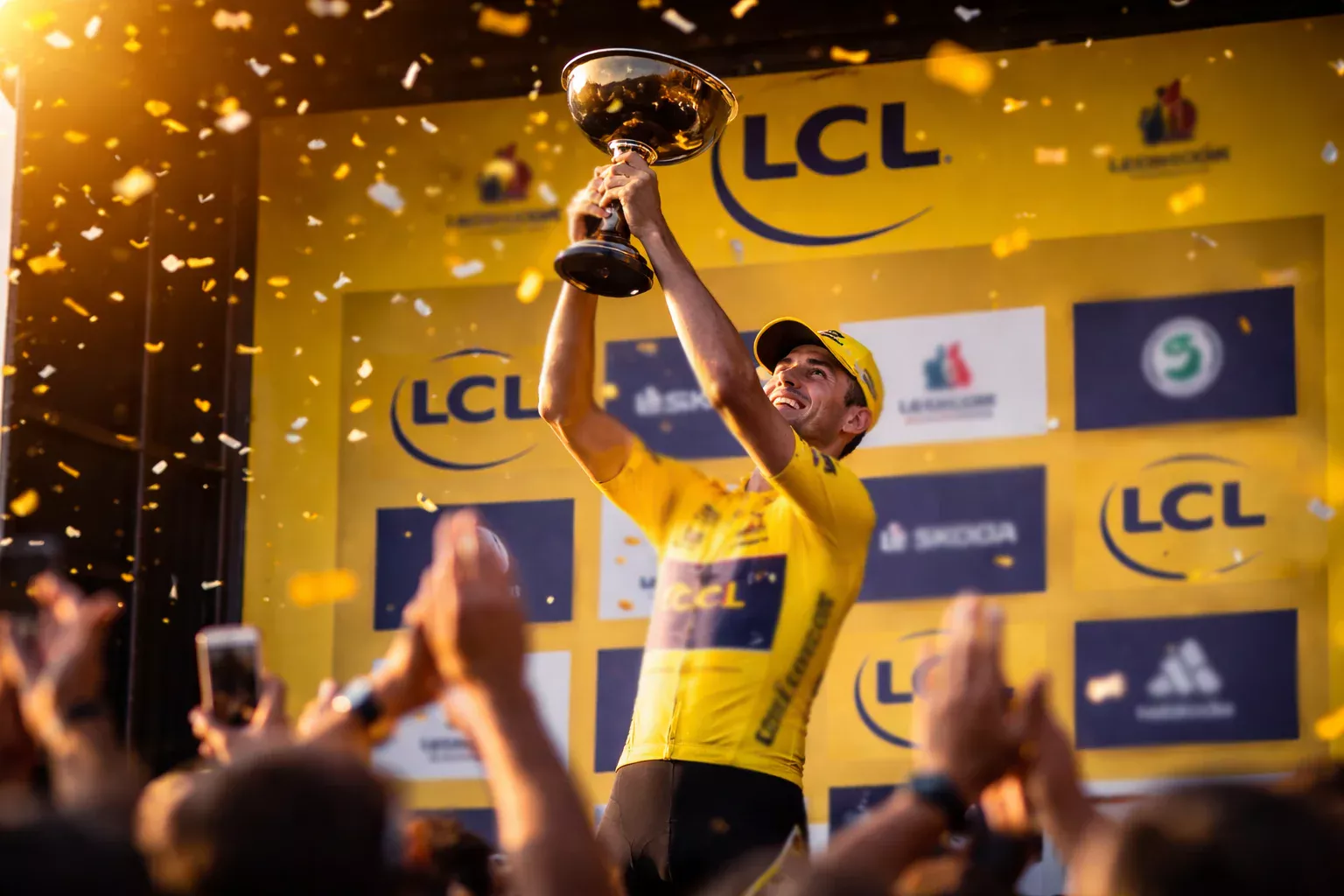 Ciclista con maillot de líder celebrando en el podio de una gran vuelta ciclista
